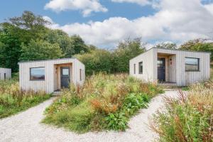 圣安德鲁斯Rustic Cabins, sea views from rewilded farm的两座小木头建筑,位于草地上