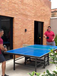 库库塔Hotel Macaw Cúcuta的两个人站在乒乓球桌旁