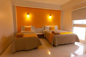 贾拉普SC HOTEL的橙色墙壁客房的两张床