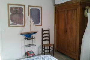 圣克莱门特德巴Bright house with garden - île de Ré的一间卧室配有一张床、一个木制橱柜和一把椅子