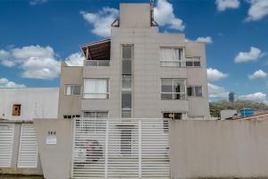 巴拉奈里奥-坎布里乌Apartamento 2 quartos com Spá Expocentro Praias的前面有栅栏的高大的白色建筑