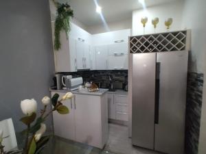 罗安达A vista perfeita的厨房配有白色橱柜和不锈钢冰箱