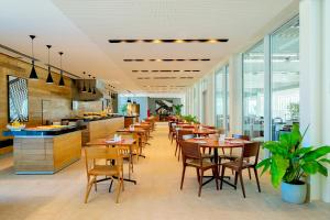里约热内卢Lagune Barra Hotel的餐厅设有木桌、椅子和窗户。