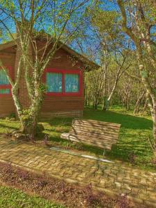 大普拉亚Pousada & Camping Nativos dos Canyons的坐在房子前面的木凳