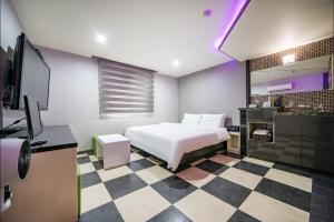 釜山MU HOTEL的卧室配有白色的床和 ⁇ 格地板