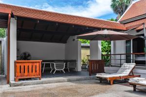 普吉镇Luxurious Residence Rawai的庭院配有遮阳伞、椅子和桌子。