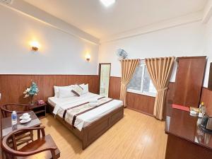胡志明市Nhat Minh Hotel - Etown and airport的一间卧室配有一张床、一张桌子和一个窗户。