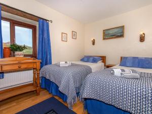 圣大卫Carn Llidi Cottage的一间卧室设有两张床、一张桌子和一个窗口。