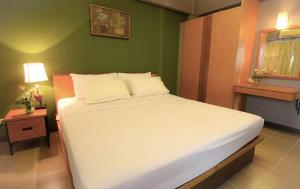莱卡邦Plai And Herbs Suvarnabhumi Airport的一间卧室设有一张白色大床和绿色的墙壁