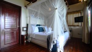爱妮岛拉斯特弗龙蒂尔海滩度假酒店 - 仅限成人的卧室配有带白色窗帘的天蓬床