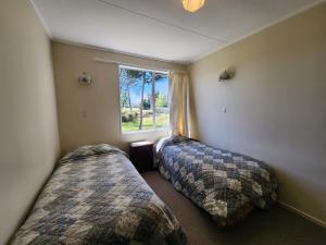马纳普里Manapouri Holiday Park的带窗户的客房内的两张床