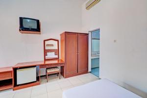 BanyubiruCapital O 93236 Hotel Hapel Negara的一间卧室配有书桌、电视和床。