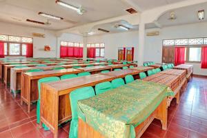 BanyubiruCapital O 93236 Hotel Hapel Negara的配有木桌和绿色椅子的教室