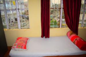 古瓦哈提Guwahati Lodge Guwahati的红色窗帘和窗户的房间里一张床位