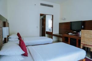 古鲁瓦尤尔Devaragam的酒店客房设有两张床和电视。