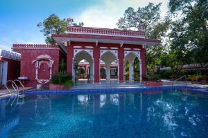 布什格尔Bageecha Resort的一座红色建筑前的游泳池