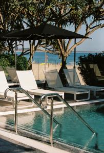 努萨角71 Hastings Street - Beachfront的海滩旁的游泳池配有两把椅子和一把遮阳伞