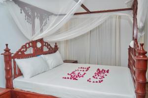 马林迪Beach Way Villa的一间卧室,床上有粉红色的鲜花