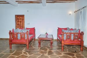 马林迪Beach Way Villa的客厅配有2把红色椅子和桌子