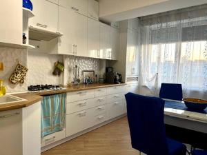 基希讷乌Airport-apartament 24&24 Chişinău!!!的厨房配有白色橱柜和蓝色椅子