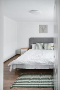TeşilaAcasă la Doftana的一间卧室配有一张带白色床单和地毯的床。