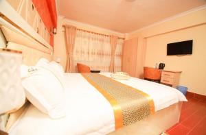 纳库鲁Gold Suite Hotel的卧室配有一张白色大床和电视。