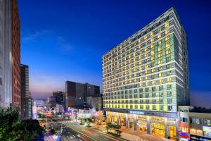 济州市Gloucester Hotel Jeju的夜幕降临的城市街道上一座高楼