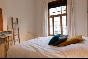根特Bohemian city loft的卧室配有带枕头的床铺和窗户。