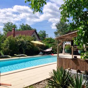 多尔多尼河畔博利厄Dordogne Farmhouse的一座带凉亭的游泳池,位于一座房子旁边