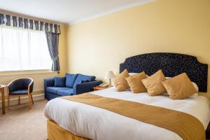 蒂弗顿Tiverton Hotel Lounge & Venue formally Best Western的一间卧室配有一张大床和一张蓝色椅子
