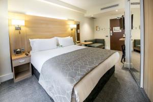 伦敦Holiday Inn London Kensington High St., an IHG Hotel的酒店客房设有一张大床和一间浴室。