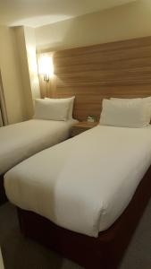 伦敦Holiday Inn London Kensington High St., an IHG Hotel的配有2张床铺的酒店客房,提供白色床单和枕头