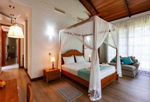 昂斯拉齐奥Anse Lazio Lodge的一间卧室配有天蓬床和沙发