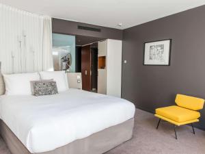 巴黎Molitor Hôtel & Spa Paris - MGallery Collection的卧室配有白色的床和黄色椅子