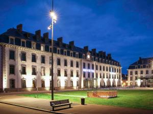 圣布里厄Novotel Saint Brieuc Centre Gare的一座在晚上有长凳的建筑