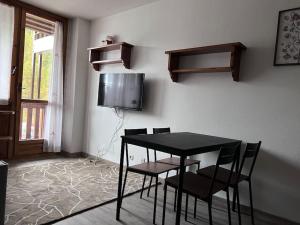 博格塔塞斯特雷da Robi appartamento fronte piste的一间配有电视的客房内的一张黑桌子和椅子