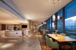 淄博淄博鼎成希尔顿花园酒店的餐厅设有桌椅和大窗户。