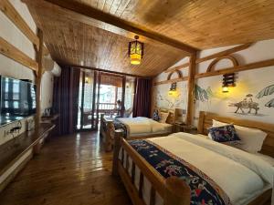 张家界Mountain View Guesthouse的一间带三张床的卧室,位于带木制天花板的房间内