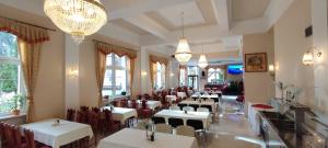 图尔钱斯凯特普利采Hotel Vyšehrad的餐厅设有白色的桌椅和吊灯。