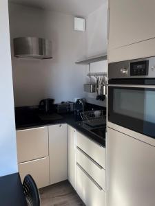 旺斯Studio indépendant的厨房配有白色橱柜和黑炉灶烤箱。