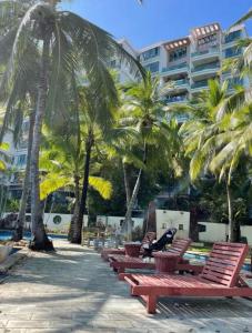 ShuijiaoSunny Apartment, minutes to beach的一排种满棕榈树的红色长椅和一座建筑