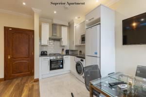 伦敦Stylish Apartment Kensington的厨房配有白色家电和玻璃桌