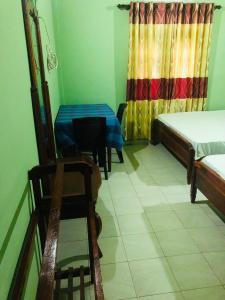 阿努拉德普勒River Garden Hotel Anuradhapura的一间设有两张床、一张桌子和一把椅子的房间