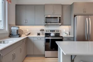 卡尔加里Luxurious Modern Home With King Bed & Office的厨房配有白色橱柜和不锈钢用具