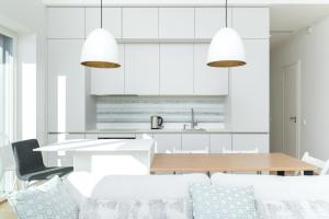塔林Brand new 2bdroom Free Parking Apartment的厨房以及带白色橱柜和桌椅的用餐室。