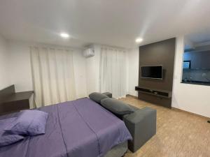 索罗卡巴Studio Super localizaçao的一间卧室配有紫色的床和一台平面电视