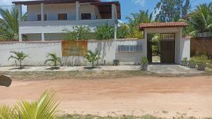 马塔迪圣若昂Residencial Jardim Imbassai 4 apt mobiliado com piscina的一座白色的房子,有门和棕榈树
