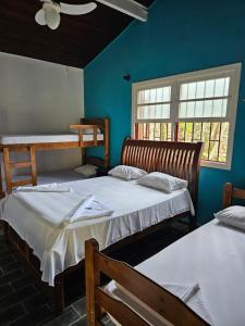 乌巴图巴Pousada da Mary的配有两张床铺的蓝色墙壁和两扇窗户