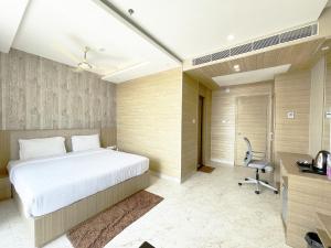 普里Hotel TBS ! PURI all-rooms-sea-view fully-air-conditioned-hotel with-lift-and-parking-facility breakfast-included的一间卧室配有一张床、一张桌子和一把椅子