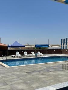Al KarāmahCali Chalet的一个带躺椅的游泳池和一个游泳池